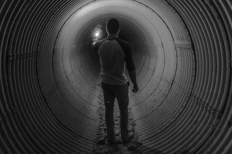 Mann geht im Tunnel mit Licht voran